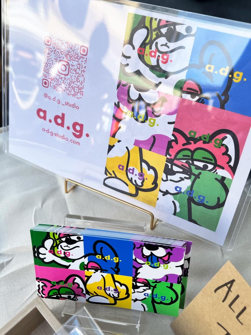 〈a.d.g.〉のカードとステッカー。6犬種のグラフィックが色面の上に並ぶ