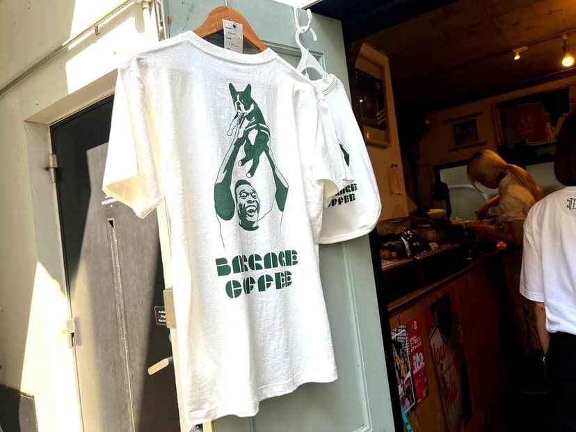 犬を掲げる選手がプリントされたBAGGAGE COFFEEのTシャツ